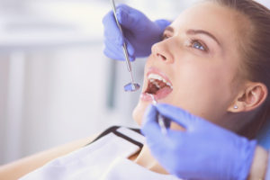 Paciente con la boca abierta examinando la inspección dental en la oficina del dentista.